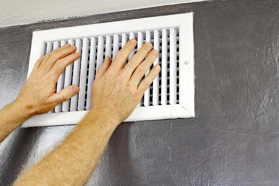Why Is My Air Conditioner Blowing Hot Air? Vent blowing hot air with hands.