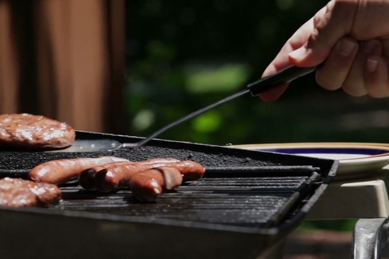 burgers and hot dogs being cooked on an outdoor grill.